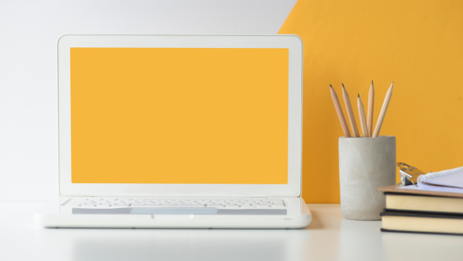 Uz galda ir portatīvais dators ar dzeltenas krāsas ekrānu, blakus tam ir grāmatas un trauks ar zīmuļiem